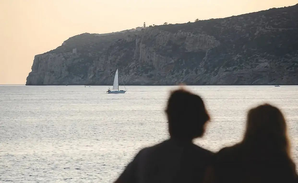 Pareja contemplando el atardecer frente al mar