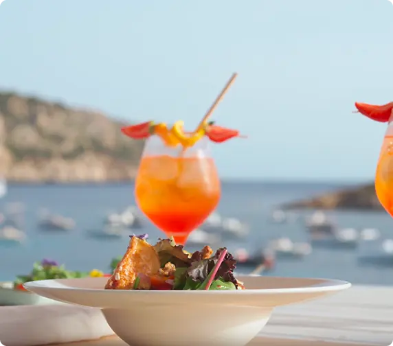 Orange cocktail and dish overlooking the bay