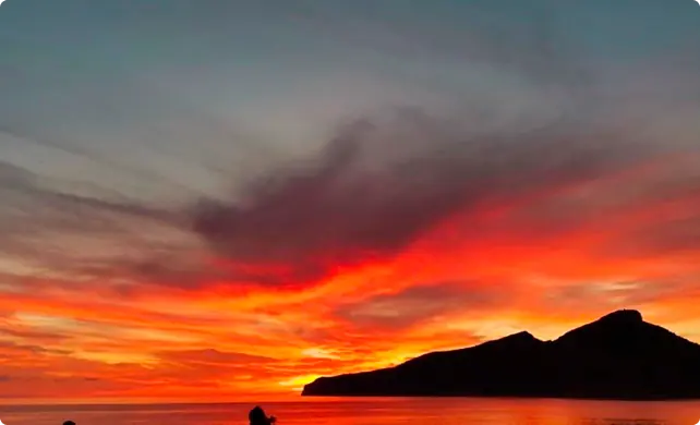 Atardecer rojo sobre el mar con la silueta de la Dragonera