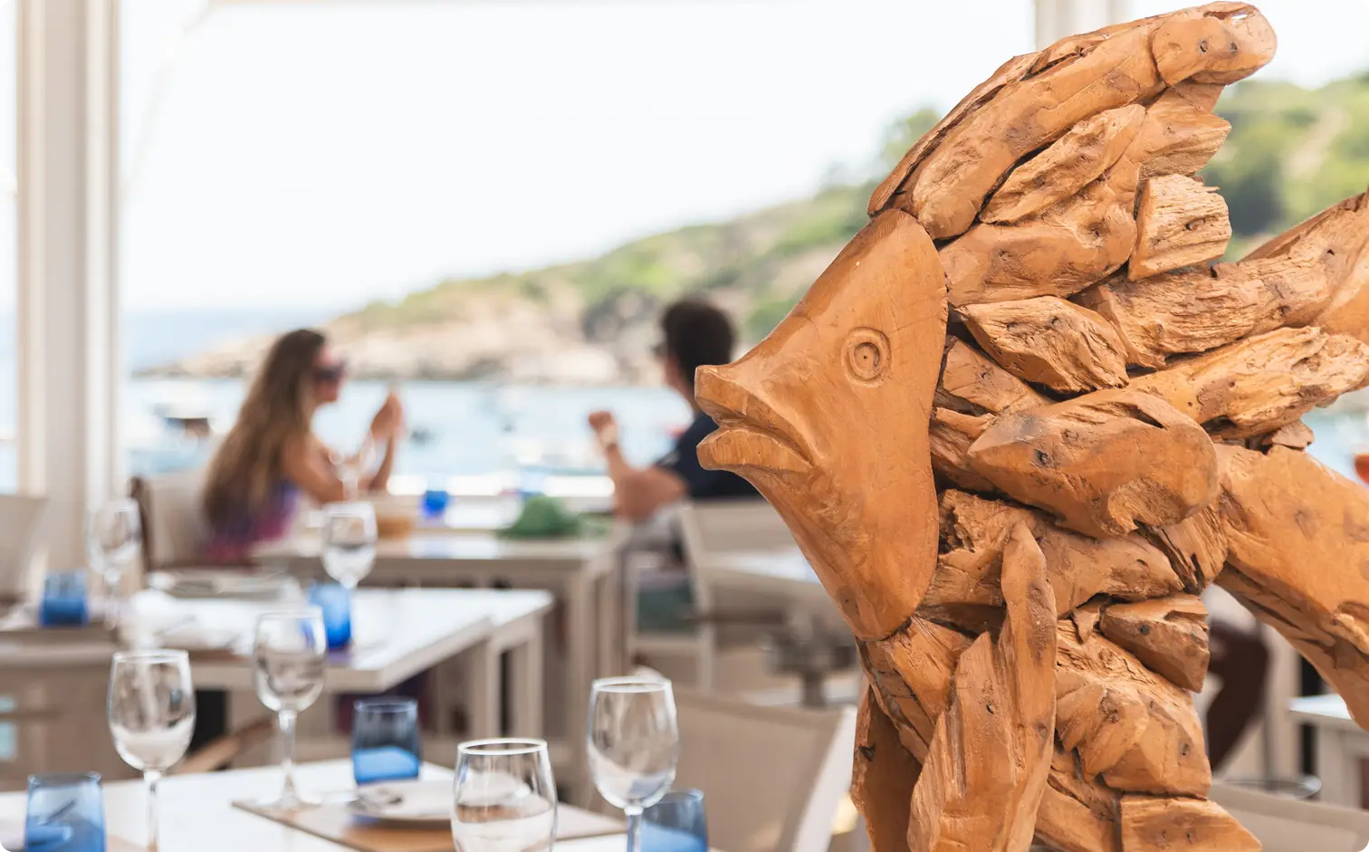 Diners on the terrace next to a carved wooden fish sculpture